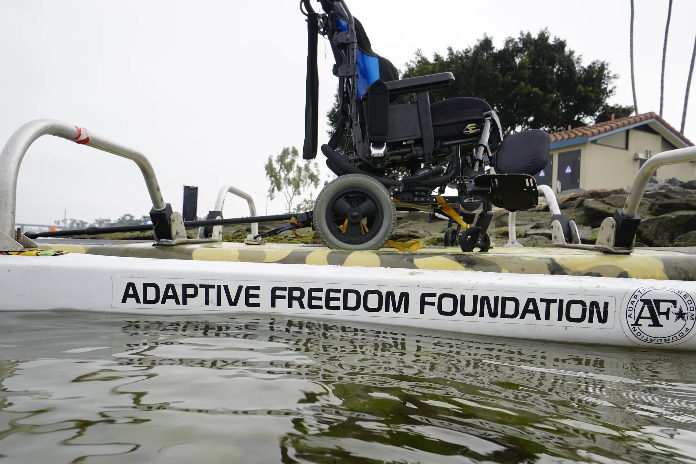 A wheelchair secured to an AFF adaptive paddleboard at the waterline