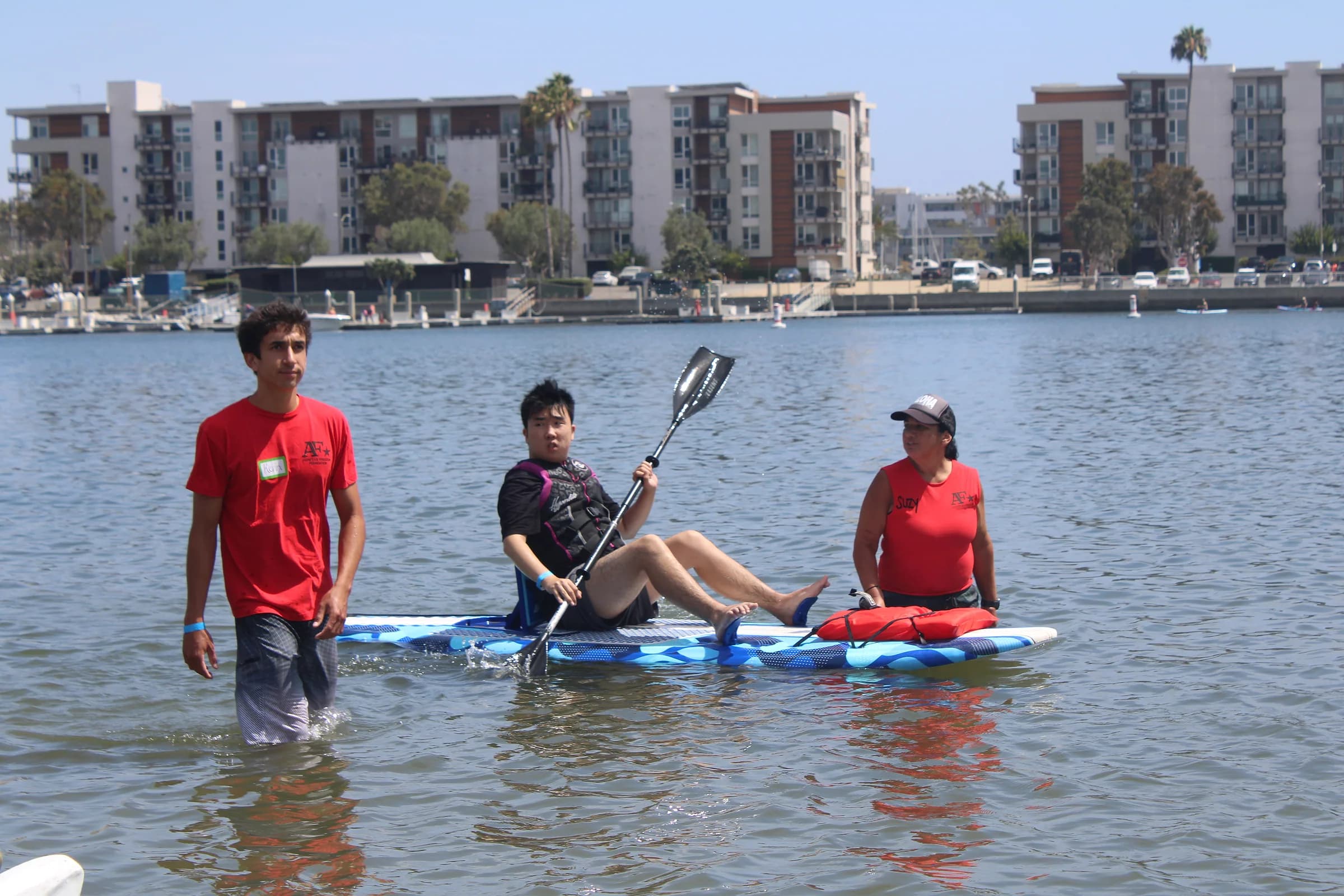 A participant paddling while two AFF volunteers guide the adapted board