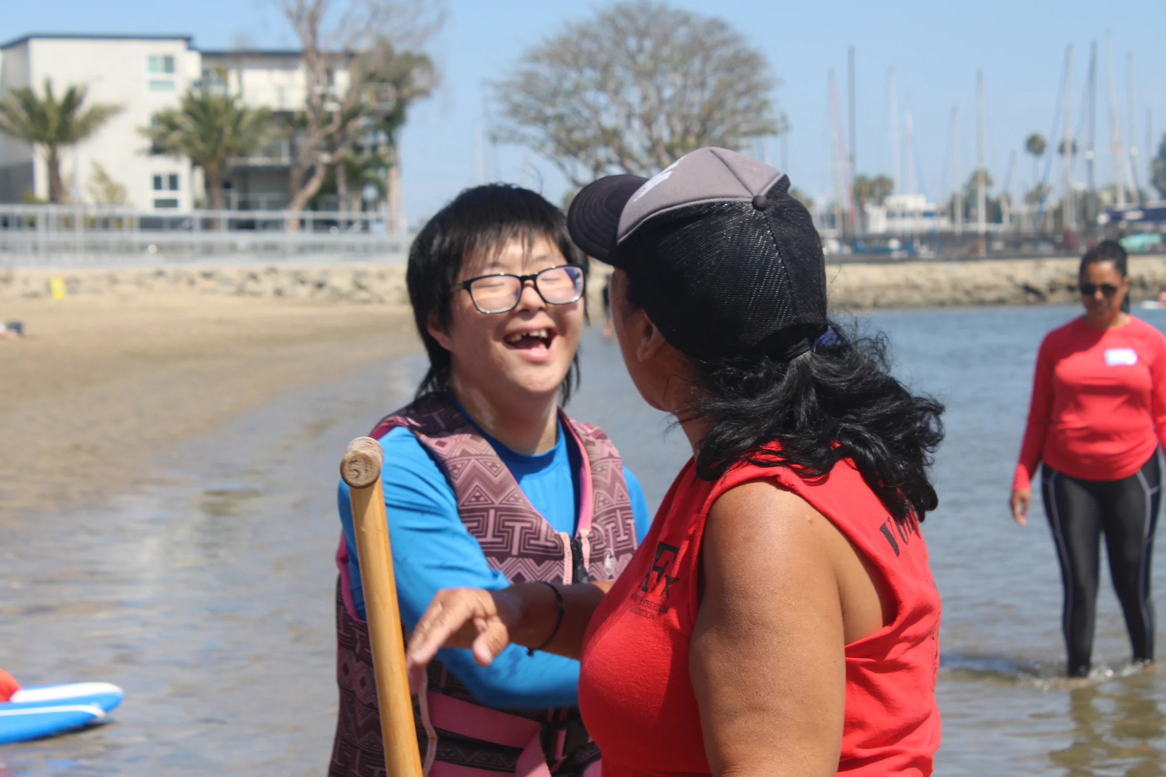 A participant laughing with an AFF volunteer beside the water