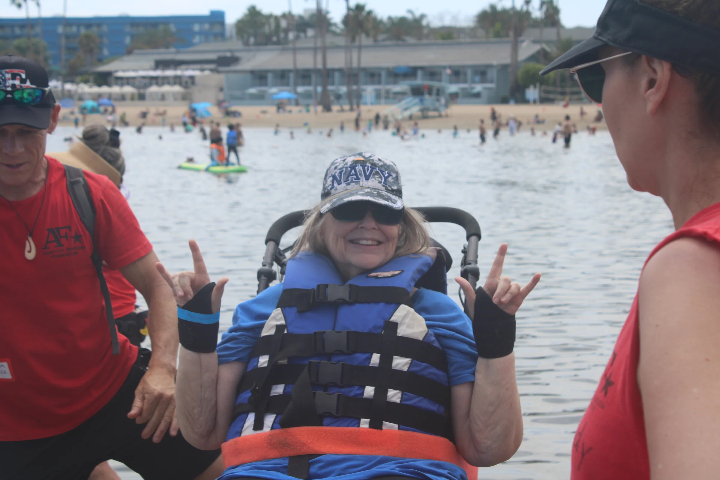 A smiling participant in adaptive equipment surrounded by the AFF launch crew